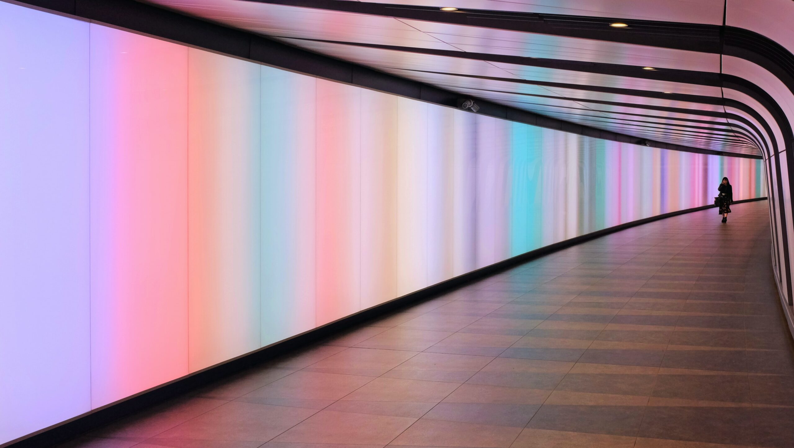 Woman stands inside a corridor lit up by neon fluorescent lights. Source: Kevin Connor from Unsplash